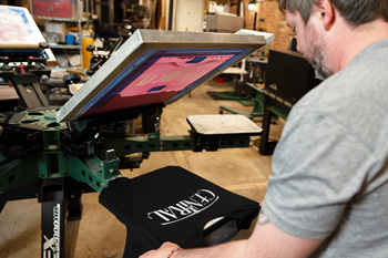 Michael transfers a printed shirt from the press to the dryer.