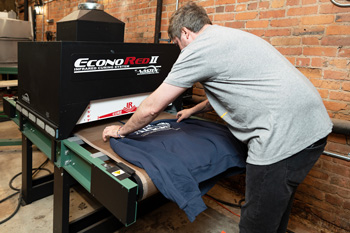 Michael loads a shirt onto the infrared conveyor dryer with adjustable heater height for bulky garments.